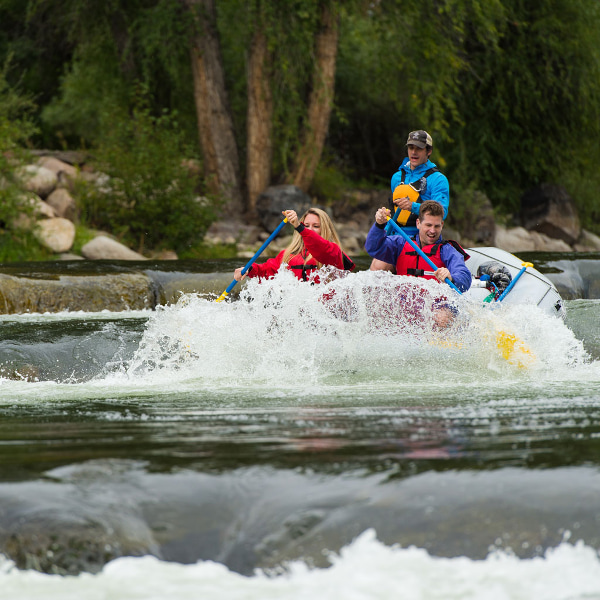 Three people rafting down a rapid